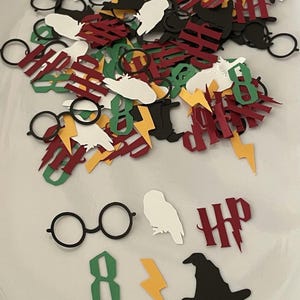 May include: Assorted paper cutouts in various colors, including black, white, red, green, and yellow. The cutouts feature shapes like glasses, owls, lightning bolts, and the letters "HP" and the number "8".