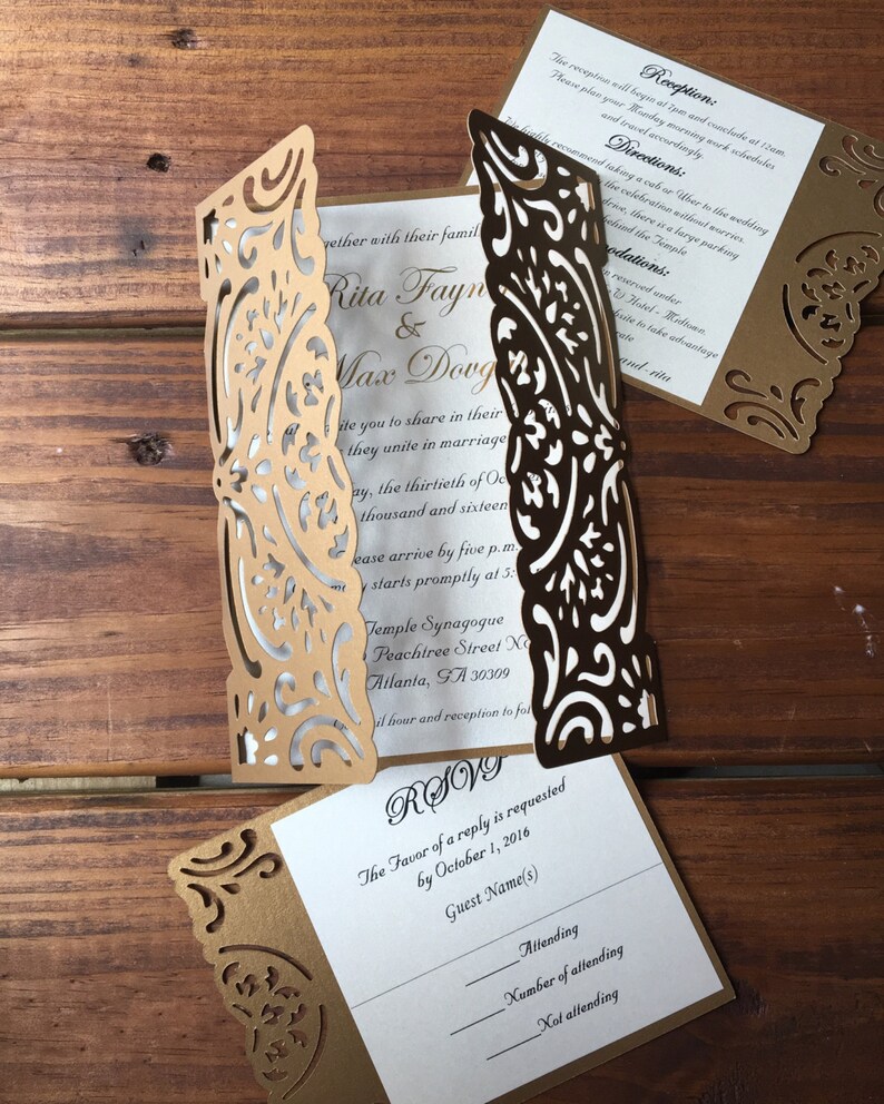 May include: A gold laser-cut gatefold wedding invitation set with white inserts featuring black text. The invitation includes details for Rita Fayne and Max Dovg, a reception card, and an RSVP card with lines for guest names and attendance status.