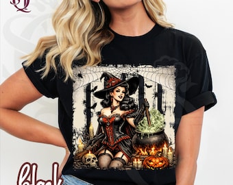 May include: A black t-shirt featuring a graphic print of a witch in a corset and hat stirring a bubbling cauldron. The design includes a spider web background, bats, lit candles, a skull, and a jack-o'-lantern at the base of the cauldron.