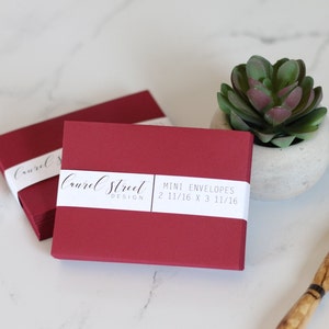 May include: A stack of burgundy mini envelopes with a white label that reads "Courvel Street Design MINI ENVELOPES 2 11/16 x 3 11/16"