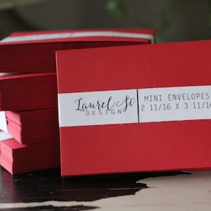 May include: A stack of red mini envelopes with a white label that reads "Laurel St. Design" and "Mini Envelopes 2 11/16 x 3 11/16"