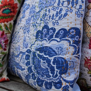 May include: Three decorative throw pillows with floral patterns. The pillow on the left has a colorful floral pattern with pink, red, green, and yellow flowers. The middle pillow has a blue and white floral pattern. The pillow on the right has a pink, red, and green floral pattern.