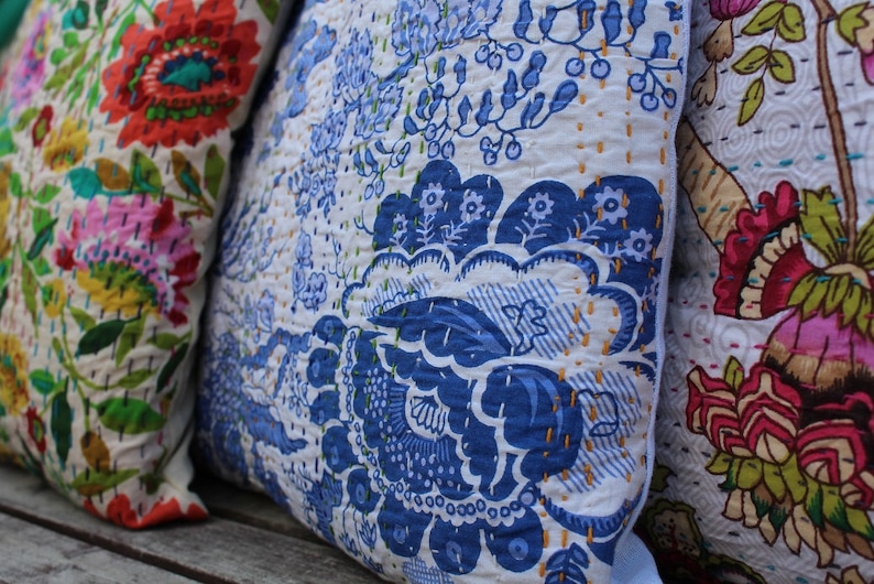 May include: Three decorative throw pillows with floral patterns. The pillow on the left has a colorful floral pattern with pink, red, green, and yellow flowers. The middle pillow has a blue and white floral pattern. The pillow on the right has a pink, red, and green floral pattern.