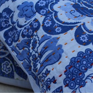 May include: Two blue and white patterned throw pillows with intricate embroidery. The pillows are made of a soft cotton fabric and feature a floral design.