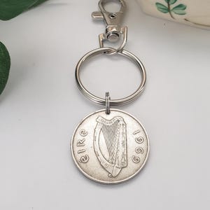 May include: Silver keychain featuring a 1969 Irish coin with a harp design and the word "EIRE" inscribed around the edge.