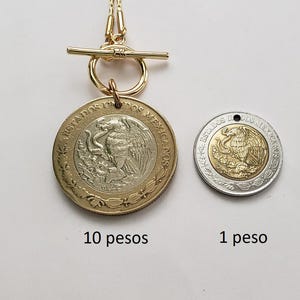K&ouml;nnte beinhalten: Eine goldfarbene Knebelkette mit einem 10-Pesos-M&uuml;nzanh&auml;nger. Daneben liegt eine 1-Peso-M&uuml;nze. Beide M&uuml;nzen zeigen den Text ESTADOS UNIDOS MEXICANOS und ein Adleremblem. Die 10-Pesos-M&uuml;nze ist an der goldfarbenen Kette befestigt.