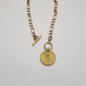 May include: A gold chain necklace with a gold coin pendant featuring the Irish harp and the text "&euro;1 EURO 2002".