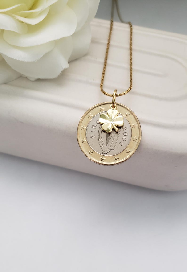 May include: Gold necklace with a 2002 Irish Euro coin pendant featuring a harp and a gold four-leaf clover charm.