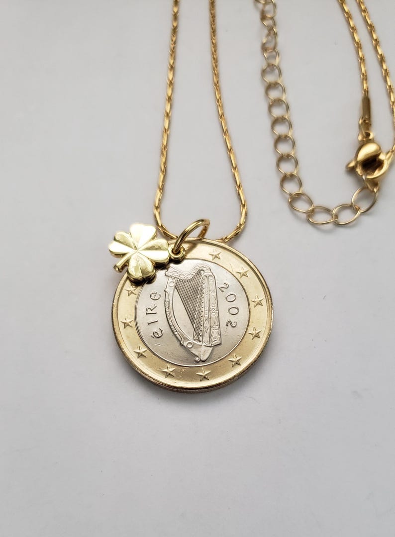 May include: A gold chain necklace with a gold shamrock charm and a 2002 Irish euro coin pendant featuring a harp.