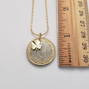May include: A gold chain necklace with a gold shamrock charm and a 2002 Irish euro coin pendant. The coin features a harp and the word "EIRE".