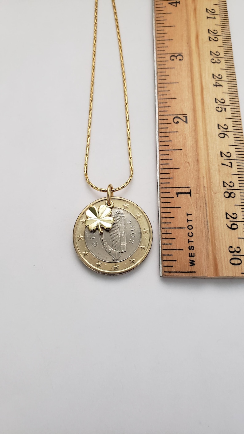 May include: A gold chain necklace with a gold shamrock charm and a 2002 Irish euro coin pendant. The coin features a harp and the word "EIRE".