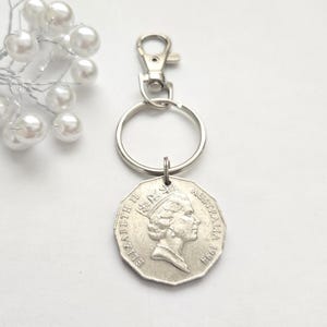 May include: Silver keychain with a silver Australian 50 cent coin featuring Queen Elizabeth II and the year 1994. The coin is attached to a silver key ring and a silver lobster clasp.