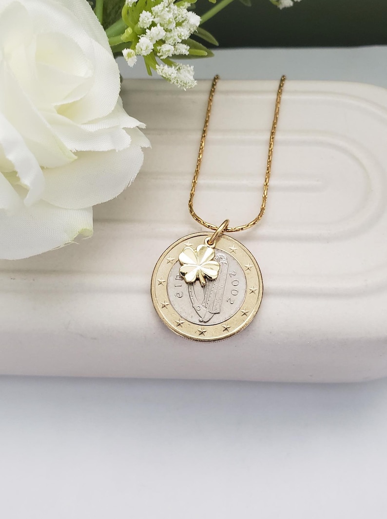 May include: Gold necklace with a gold shamrock charm and a 2002 Irish euro coin pendant featuring a harp.