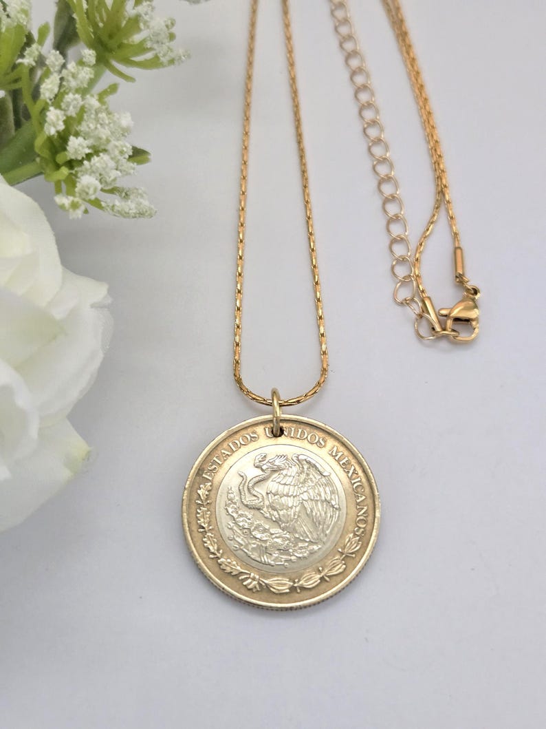 K&ouml;nnte beinhalten: Eine goldfarbene Halskette mit einem runden Anh&auml;nger aus einer mexikanischen M&uuml;nze. Die M&uuml;nze zeigt ein silberfarbenes Zentrum mit einem Adleremblem und einen goldfarbenen Rand mit dem Text "ESTADOS UNIDOS MEXICANOS".