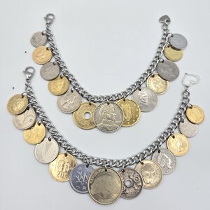 Pode incluir: Duas pulseiras de corrente de metal prateado com v&aacute;rias moedas internacionais como pingentes. As moedas s&atilde;o uma mistura de cores douradas e prateadas, exibindo diferentes retratos, s&iacute;mbolos e textos. Cada pulseira tem um fecho de metal.