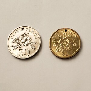 May include: Two Singaporean coins, one gold and one silver. The gold coin is a one dollar coin with a flower design and the text "ONE DOLLAR". The silver coin is a fifty cents coin with a flower design and the text "FIFTY CENTS".