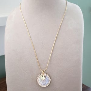 May include: A gold chain necklace with a gold coin pendant featuring a shamrock charm. The coin is a 2 Euro coin from 2002.