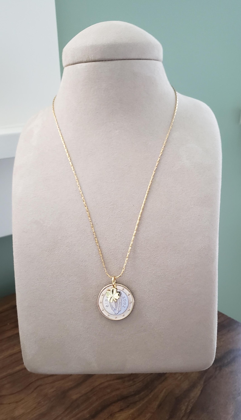 May include: A gold chain necklace with a gold coin pendant featuring a shamrock charm. The coin is a 2 Euro coin from 2002.