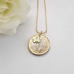 May include: A gold chain necklace with a gold shamrock charm and a 2002 Irish euro coin pendant featuring a harp.