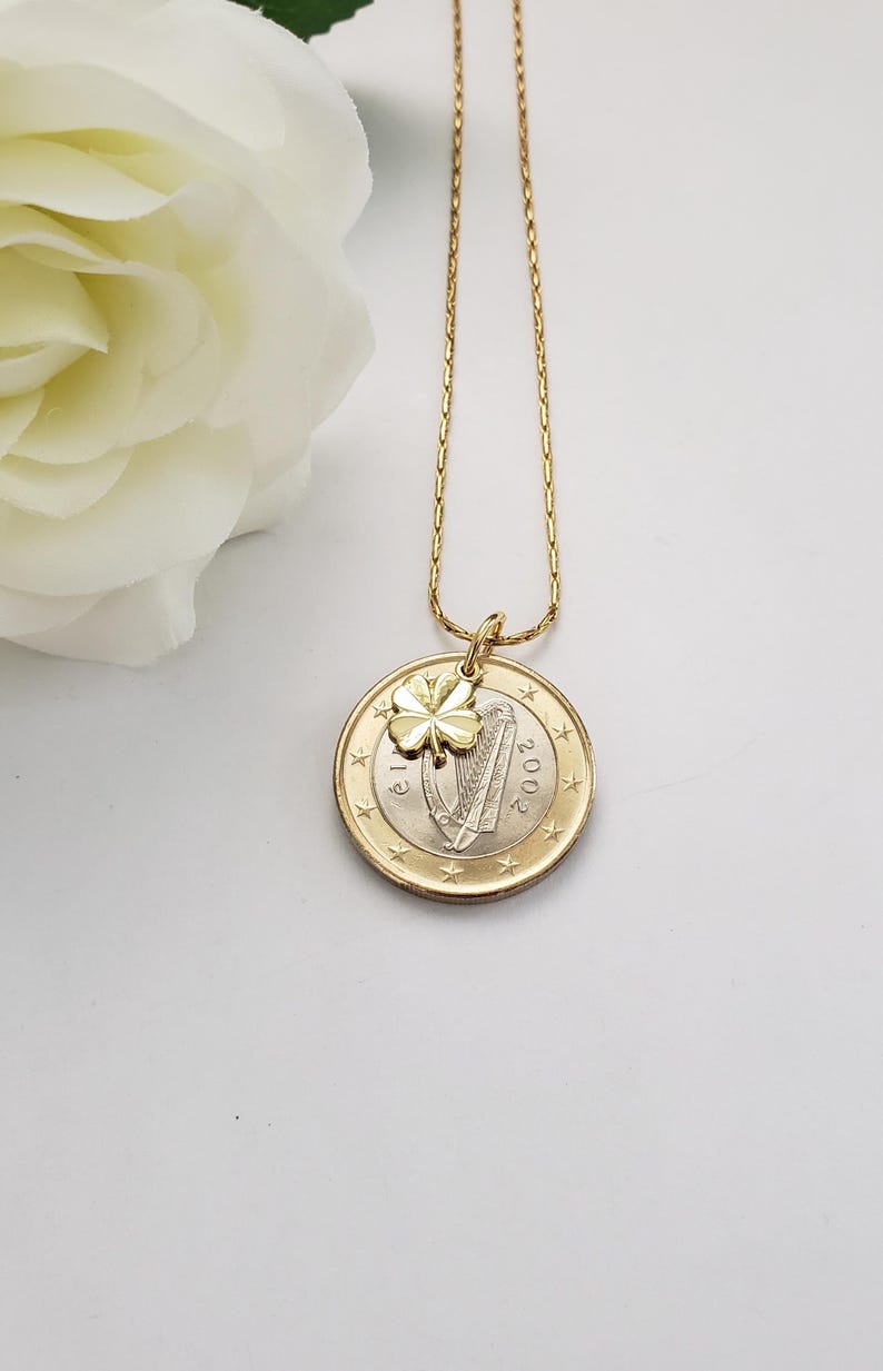 May include: A gold chain necklace with a gold shamrock charm and a 2002 Irish euro coin pendant featuring a harp.