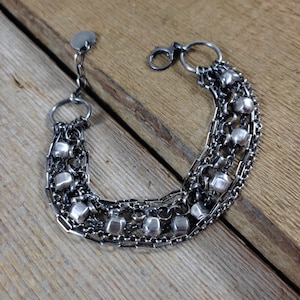 May include: A silver bracelet with multiple chains and small, round beads. The bracelet has a clasp closure.