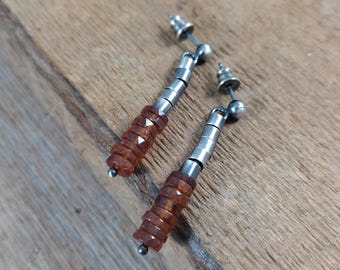 Op de afbeelding: Een paar oorhangers met een zilverkleurig metalen ontwerp. Elke oorbel heeft een reeks kleine, facetgeslepen, amberkleurige kralen die op elkaar zijn gestapeld. De oorbellen hebben een post-back sluiting en een kleine zilveren bal aan de onderkant.