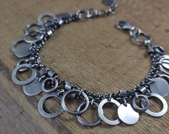 May include: A silver bracelet with multiple layers of chain and dangling circles and discs.