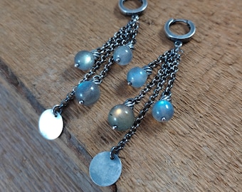 Peut inclure: Une paire de boucles d'oreilles pendantes en argent avec plusieurs chaînes et des perles de pierres précieuses bleu-gris irisées. Les boucles d'oreilles ont un disque circulaire au bas.