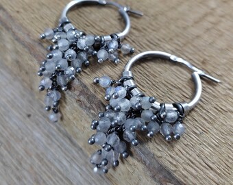 Peut inclure: Boucles d'oreilles créoles en argent avec un groupe de petites perles de pierre de lune claires qui pendent de chaque créole.