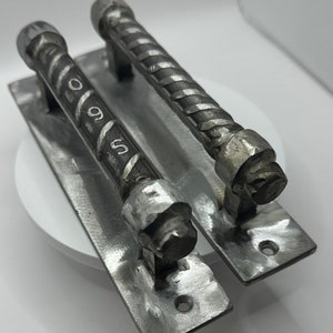 May include: Two silver metal door handles with a twisted design. The handles are attached to rectangular metal plates.