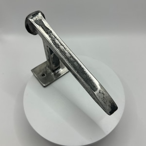 May include: A silver metal towel rack with a rustic, hammered finish. The rack is mounted to a wall and has a single bar.