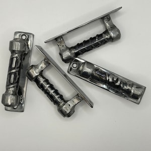 May include: Four silver metal door handles with a twisted design. The handles are attached to rectangular plates.