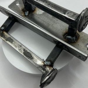 May include: Two rustic metal door handles with a nail design. The handles are made of metal and have a hammered finish. The nails are welded to the handles and are a decorative element.