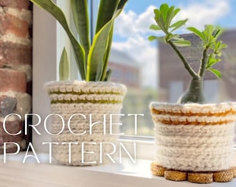 Puede incluir: Dos fundas de ganchillo cilíndricas para macetas en hilo color blanco roto con rayas horizontales en verde oliva y amarillo mostaza. Las fundas presentan un patrón de punto grueso y texturizado sobre un alféizar. El texto CROCHET PATTERN es visible.