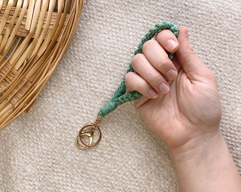 May include: A green braided keychain with a gold key ring. The keychain is made of a soft, woven material.