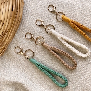 May include: Four keychains with gold key rings and braided cords in green, beige, white, and yellow.