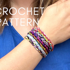 May include: A close-up of a person's wrist wearing a stack of colourful crocheted bracelets. The bracelets are made with a variety of different coloured yarns and are all braided together. The text "CROCHET PATTERN" is superimposed on the image.