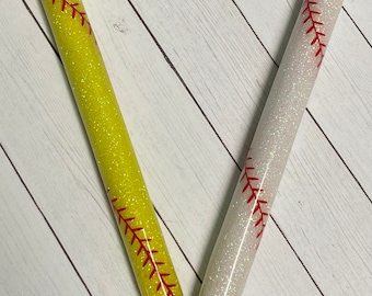 May include: Two glitter pens with a baseball stitch design. One pen is yellow with red stitching and the other is white with red stitching.