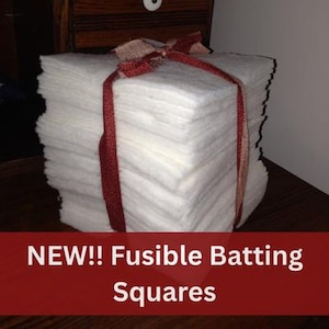 May include: A stack of white fusible batting squares tied with a red ribbon.  NEW!! Fusible Batting Squares.