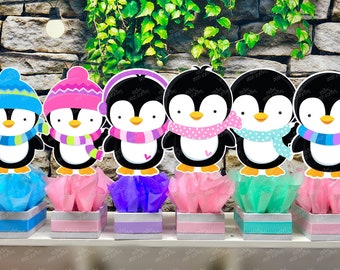 May include: Six penguin centerpieces with different colored hats and scarves. Each penguin is standing on a small box with tissue paper inside. The boxes are blue, pink, purple, pink, green, and pink.