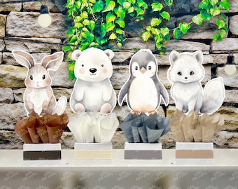 May include: Four adorable animal centerpieces featuring a brown bunny, a white polar bear, a black and white penguin, and a white arctic fox. Each animal is standing on a small, decorative base with brown, white, gray, and beige tissue paper.