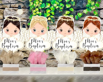 May include: Four centerpieces featuring angel wings and a cloud with the text "Mia's Baptism". Each centerpiece has a different colored tissue paper base and a different angel with blonde or brown hair.