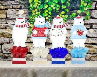 May include: Four polar bear cutouts with festive sweaters, hats, and scarves, each atop a decorative box with tissue paper. The bears have different designs, including a red and blue sweater, and a sweater with Christmas lights.