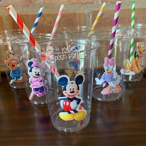 May include: Clear plastic cups with Mickey Mouse and other Disney character stickers. The cups have red and white striped straws. The cups are decorated with the text "rosies posh parties".