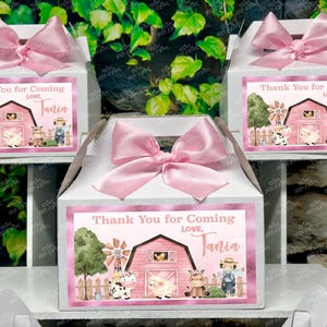 May include: White gift boxes with pink bows, each featuring a label with a pink barnyard scene and the text "Thank You for Coming, Love, Tania". The boxes are decorated with a pink ribbon.