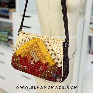 Puede incluir: Un bolso bandolera de tela acolchada con una correa marrón. El bolso está hecho de varias telas en tonos rojos, amarillos, marrones y blancos con estampados florales. El bolso tiene una etiqueta "www.blhandmade.com" en la parte inferior.