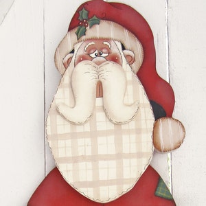 May include: A hand-painted wooden Santa Claus ornament with a red hat, white beard, and plaid pattern. The Santa has a friendly expression and is wearing a red suit with a green plaid trim.