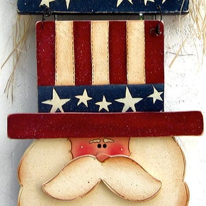 May include: Wooden welcome sign with a red, white, and blue American flag design. The sign features a white beard and a red hat with stars. The sign says "Welcome" in white letters.