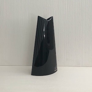 May include: A black ceramic vase with a geometric design. The vase has a narrow opening and a wide base.