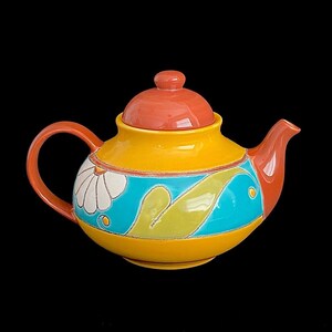 May include: A yellow teapot with a red lid and a blue and green floral design. The teapot has a rounded body and a spout on the side.